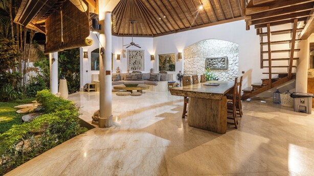 Un vaste espace intérieur doté d’un haut plafond, d’un mur en pierre et d’un escalier en bois.