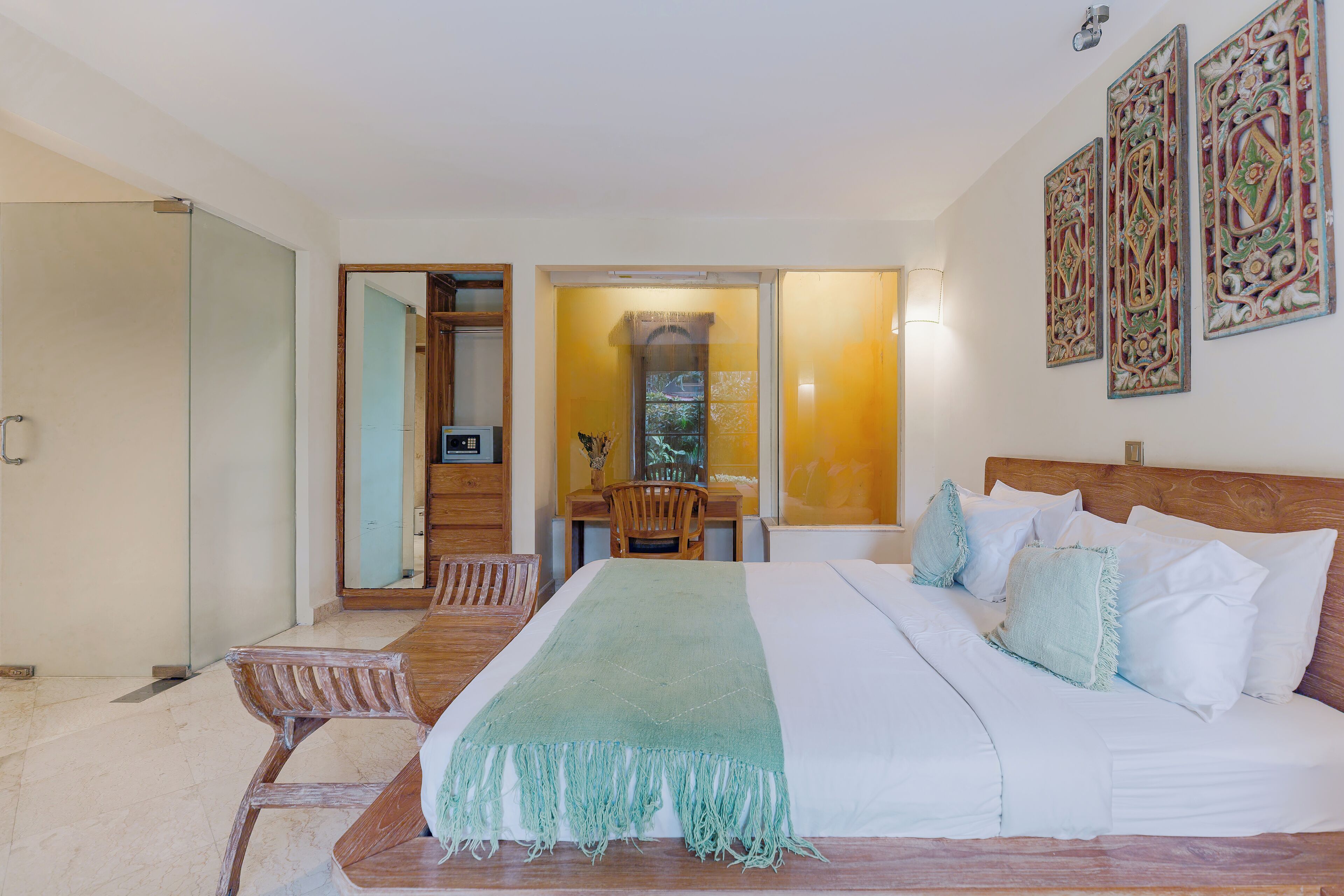 A hotel room with a large bed, a wooden headboard, a desk with a chair, and a mirror.