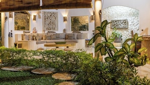 Un espace intérieur bien éclairé, avec un mur en pierre, un ensemble de canapés et diverses plantes.