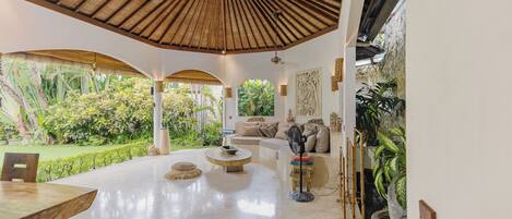 A spacious living area with a high ceiling, a round coffee table, a sofa, and a dining table.