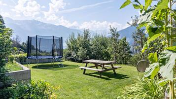A backyard with a trampoline, picnic table, and garden.