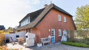 Una casa de dos pisos con techo de paja y fachada de ladrillo rojo.