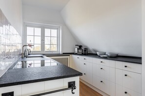 Una cocina moderna con armarios blancos, encimera negra y ventana que proporciona luz natural.