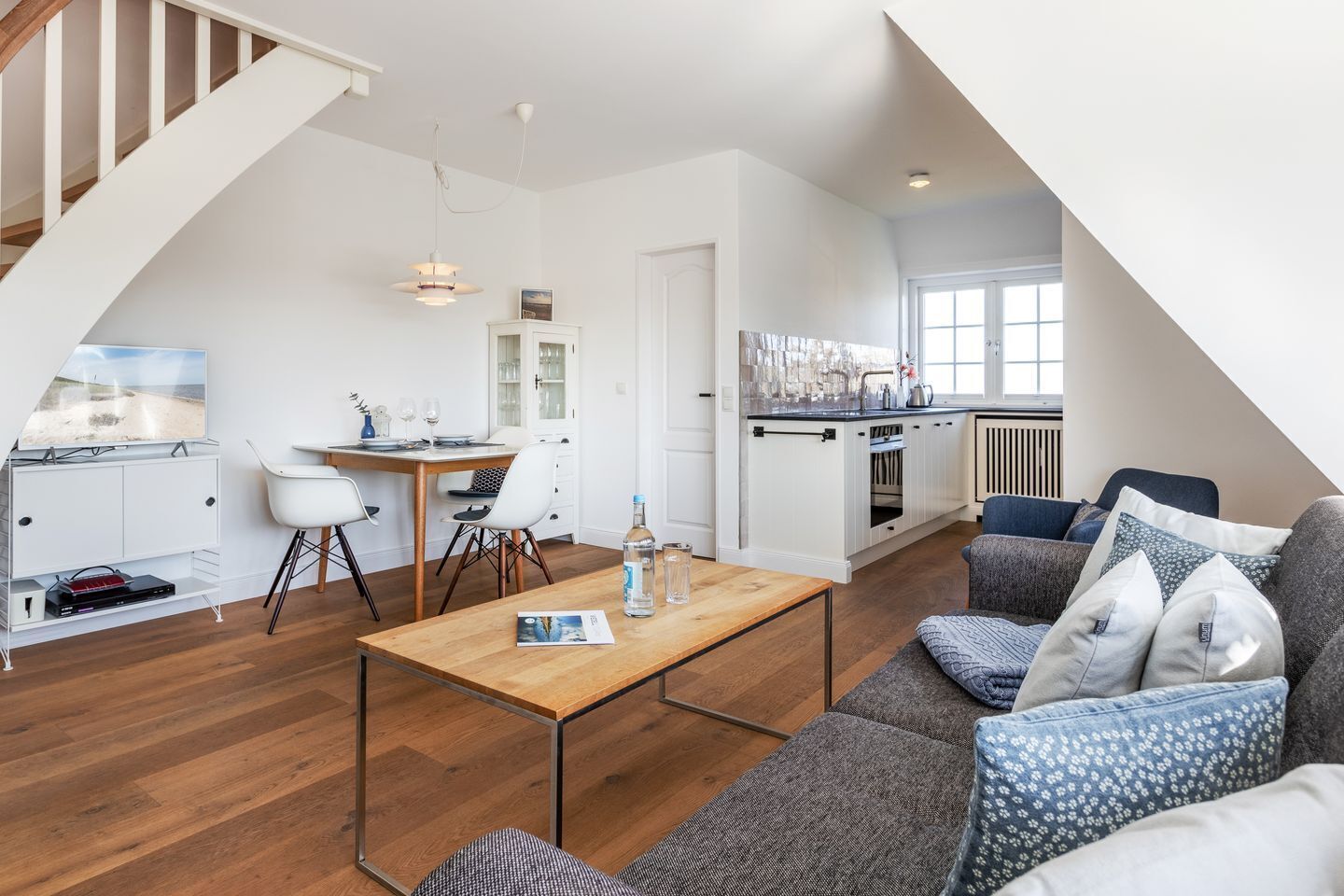 A modern apartment with a dining area, kitchen, and living room.