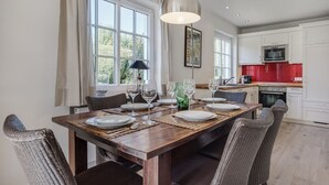 Un coin repas avec une table en bois dressée pour six personnes, entourée de chaises en osier.