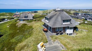 Una propiedad costera con casas de techo de paja, un camino pavimentado y vistas al mar.
