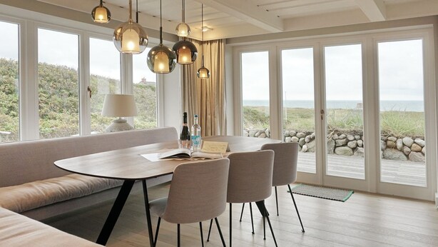 Un comedor moderno con una mesa redonda, cuatro sillas e iluminación colgante.