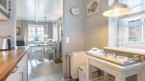 A modern kitchen with a wooden countertop, white cabinetry, a built-in oven, and a window with a view of a brick building. - Paulas Hüs - Fiete - Die Fiete, ca. 50 m² ist Besonders Liebevoll für bis zu 3 Personen (Sylt-Ost)