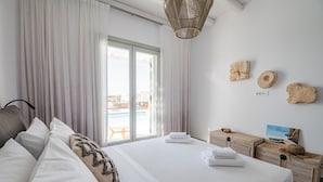 A modern hotel room with a large bed, a view of the pool, and a balcony. - Petra Mare in Mykonos (Mykonos)