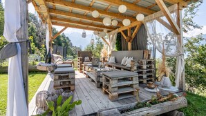 An outdoor wooden deck with rustic furniture, a covered seating area, and a view of the mountains. - Apartment 'Patztauhof Tschavalatsch' with Mountain View, Shared Garden and Wi-Fi (Sluderno BZ)