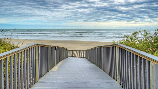 A wooden boardwalk leading to a beach with a cloudy sky. - Salt & Sun by Avantstay Beach Access + Pool (Port Aransas)