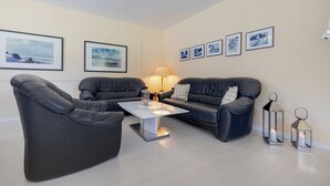Un salon moderne comprenant un ensemble de canapés, une table basse et des cadres photos accrochés au mur.