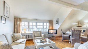A modern living room with a television, seating area, and a dining table. - Elbe, Wohnung Nr. 8 - Haus Elbe - Liebevoll Ausgestattete Obergeschoss-wohnung Unter Reet (Sylt-Ost)