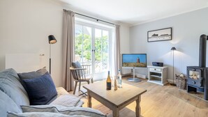 A cozy living room with a sofa, a wooden table, a television, and a fireplace.