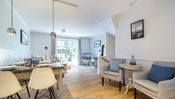A spacious living area with a dining table set for four, a sofa, and a small side table.