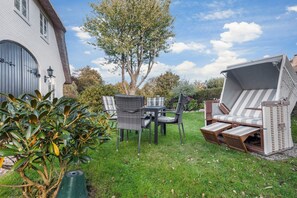 Eine Terrasse mit Gartenmöbeln, einem Grill und einem großen Baum.