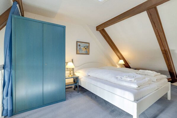 A bedroom with a bed, a nightstand, a wardrobe, and a painting on the wall.