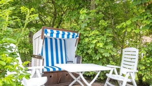 A garden patio with a striped chair, a white table, and a white chair. - Süder Ech - Süder Ech - ein Gepflegtes Haus, Zentral Gelegen (Sylt)