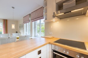 A modern kitchen with a wooden countertop, built-in oven, and stainless steel range hood. - Barig Hüs EG - Barig Hüs EG - Objekt in Einer Ruhig Gelegenen Straße in der Nähe vom Wattenmeer (Sylt-Ost)