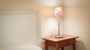 A small wooden bedside table with a lamp and a single drawer.