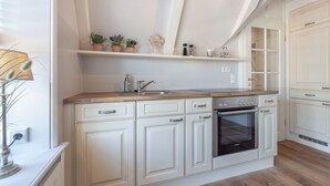 Une cuisine avec des meubles blancs, un four Bosch et un plan de travail en bois.