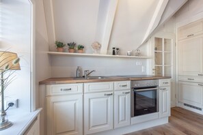 Une cuisine avec des meubles blancs, un four Bosch et un plan de travail en bois.