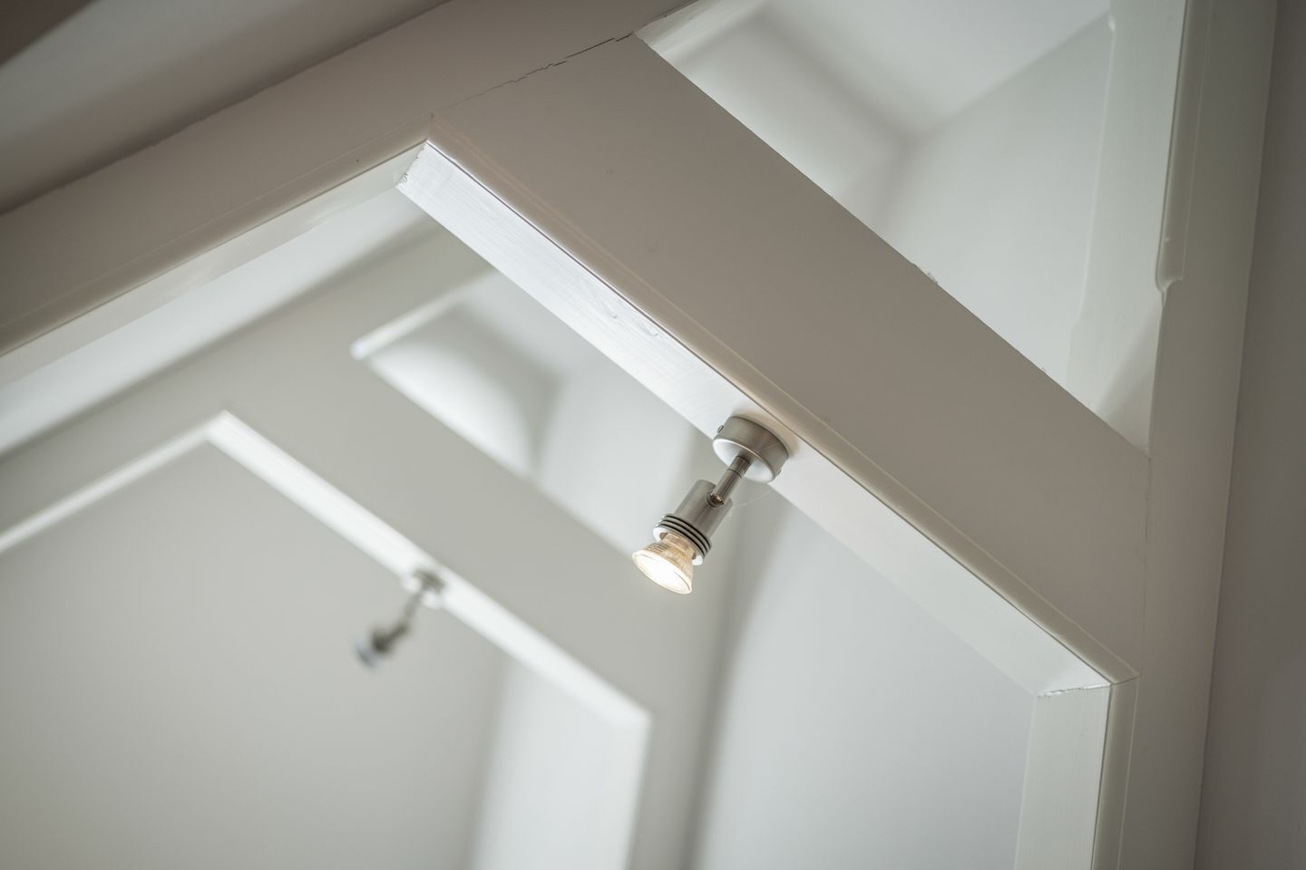 A ceiling with recessed lighting fixtures and a visible door frame.