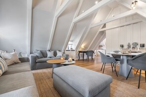 A modern loft-style living space with a dining area, high ceilings, and a kitchen in the background.