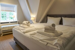 Une chambre à coucher avec un grand lit, un banc et une fenêtre équipée de stores.