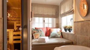 Una habitación acogedora con un banco empotrado, una bañera y un ventanal con cortinas.