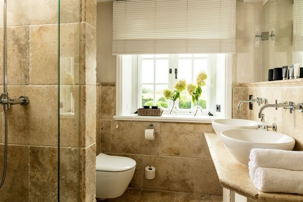Une salle de bain avec une douche, des toilettes et un lavabo. Il y a une fenêtre avec des plantes sur le rebord.