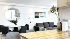 A modern kitchen with white cabinets, a wooden countertop, and a dining area with a round table and chairs. - Beach View 2 Bedrooms Apartment  (Surfers Paradise)