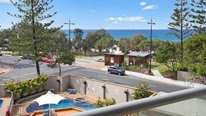 A residential area with a pool, a view of the ocean, and a street with cars. - Beach View 2 Bedrooms Apartment  (Surfers Paradise)