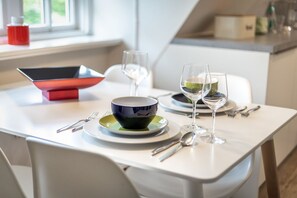 Una mesa de comedor con un bol, platos, cubiertos y copas de vino.