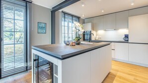 Une cuisine moderne dotée d’un îlot central, de grandes fenêtres et offrant une vue sur l’extérieur.