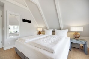 Ein Schlafzimmer mit einem großen Bett, zwei Nachttischen mit Lampen, einem Fenster mit Blick und einer Tür.