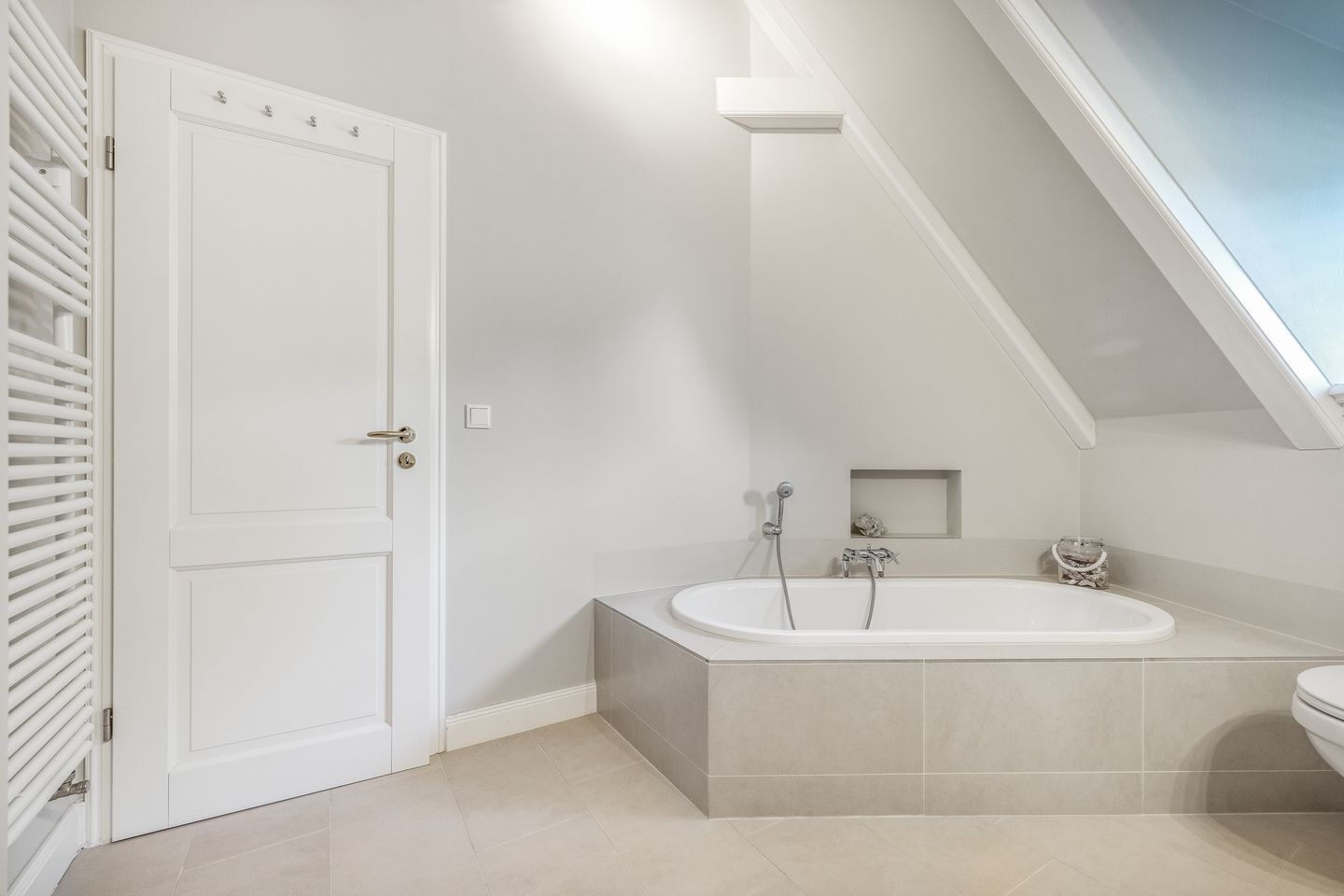 A bathroom with a freestanding bathtub, a toilet, and a door with a handle.