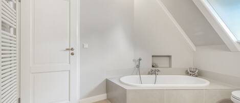 A bathroom with a freestanding bathtub, a toilet, and a door with a handle.