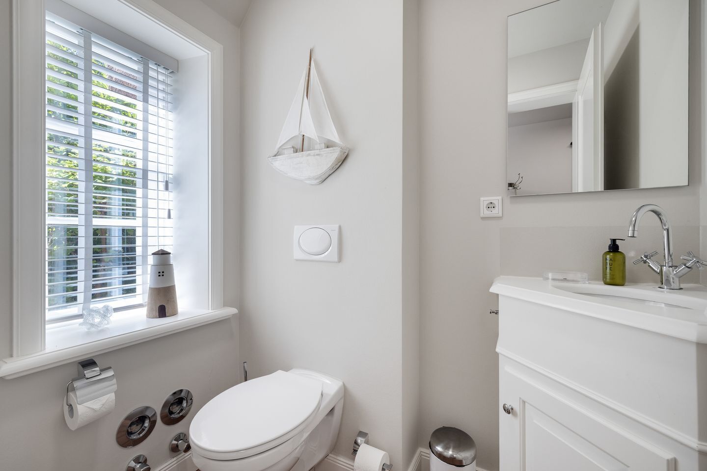 Ein Badezimmer mit Toilette, Waschbecken und einem Fenster mit Jalousien.