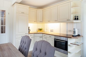 A modern kitchen with white cabinetry, a Bosch oven, and a wooden countertop.