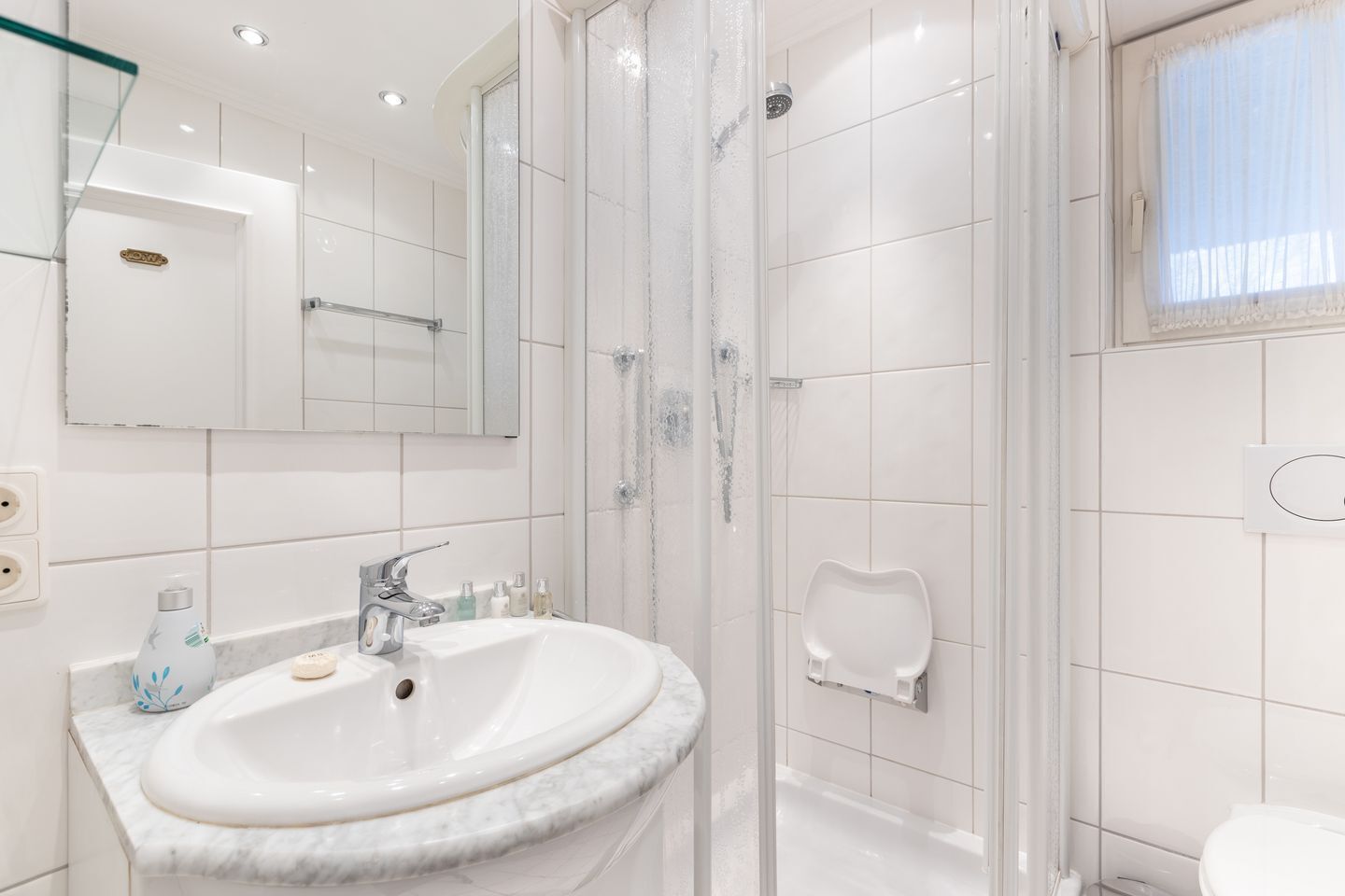 Ein modernes Badezimmer mit einem мраморному Waschbecken, einer Duschkabine und einer Toilette.