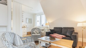 A modern living room with a sofa, two wicker chairs, a coffee table, and a lamp. - Uaster Reeg III - Studio - Sehr Gepflegte und Geschmackvoll Eingerichtete Ferienwohnungen in (Sylt / OT Archsum)