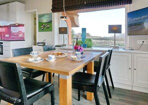 A dining area with a wooden table, black chairs, and a view of the outdoors.
