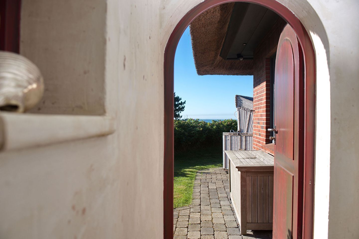 An arched doorway leading to a covered outdoor area with a brick wall and a wooden deck.