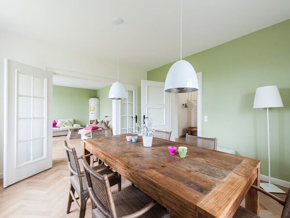 A dining area with a wooden table, wicker chairs, and pendant lights.