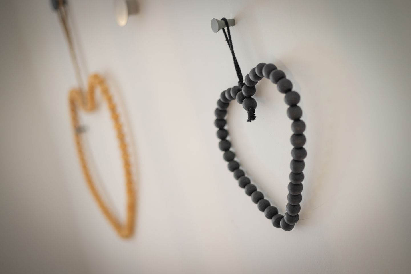 A wall with two necklaces hanging on hooks.
