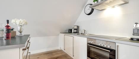 A modern kitchen with a built-in oven, stainless steel appliances, and a clock on the wall.