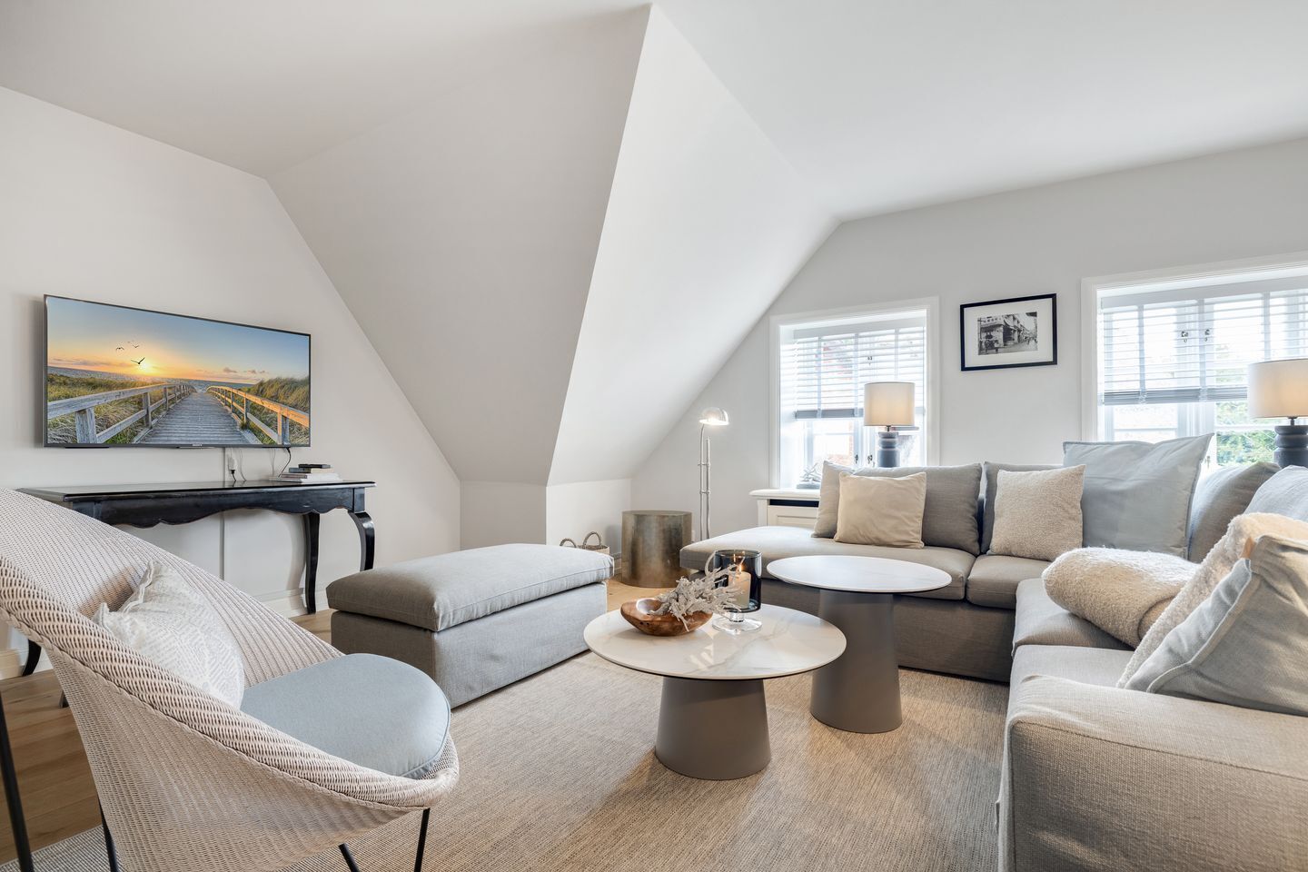 A modern living room with a high ceiling, a large TV, and a cozy seating area with a sofa and chairs.