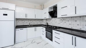 A modern kitchen with white cabinets, a black countertop, a stove, and a dishwasher. - Villa Azalea 1 in Ortaca (Ortaca)