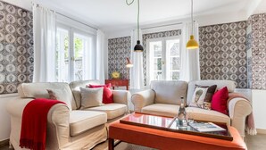 A living room with two sofas, a coffee table, and patterned wallpaper.